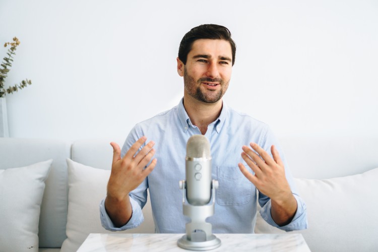 A good leader confidently speaks into a podcast microphone, sharing insights in a calm and professional setting.