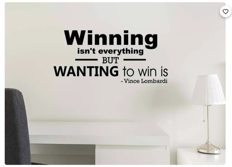 Wall decal with Vince Lombardi's truly great quote: "Winning isn't everything, but wanting to win is," displayed above a desk setup.