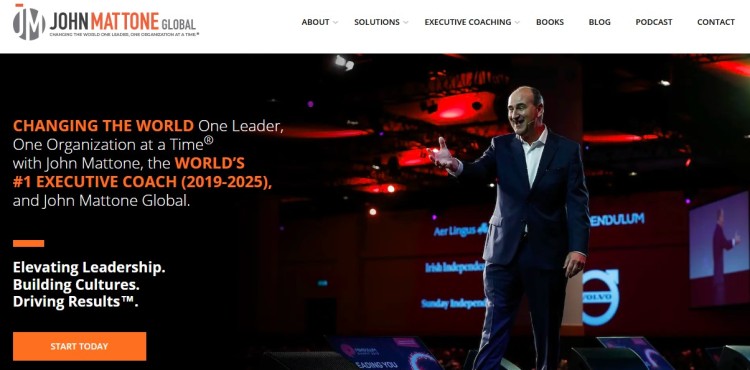 John Mattone, executive coach, delivering a keynote speech on a stage with a red-lit background