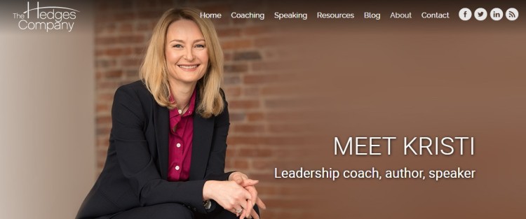Kristi Hedges, leadership coach, author, and speaker, smiling while seated, representing coaching for leaders and executive development.